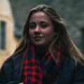 A young woman wearing a jacket with a red plaid scarf.